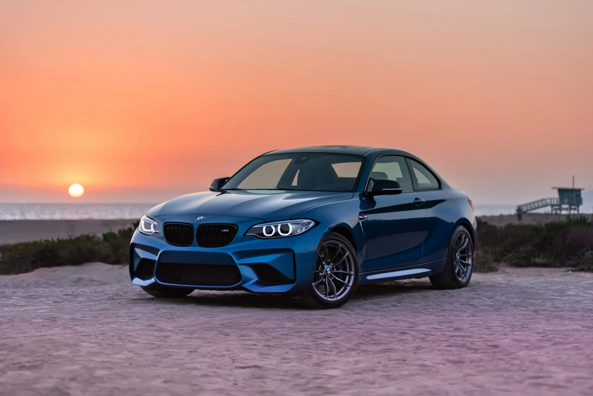 Blue BMW M2 with sunset in the background