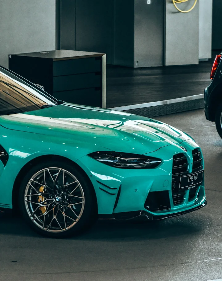 Close-up side view of a brand new turquoise BMW M4 Competition