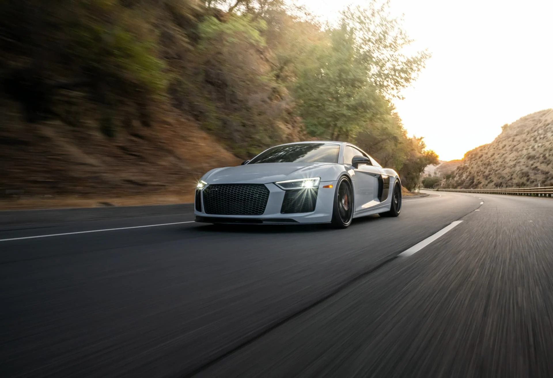 A nardo grey Audi R8 driving down a country road