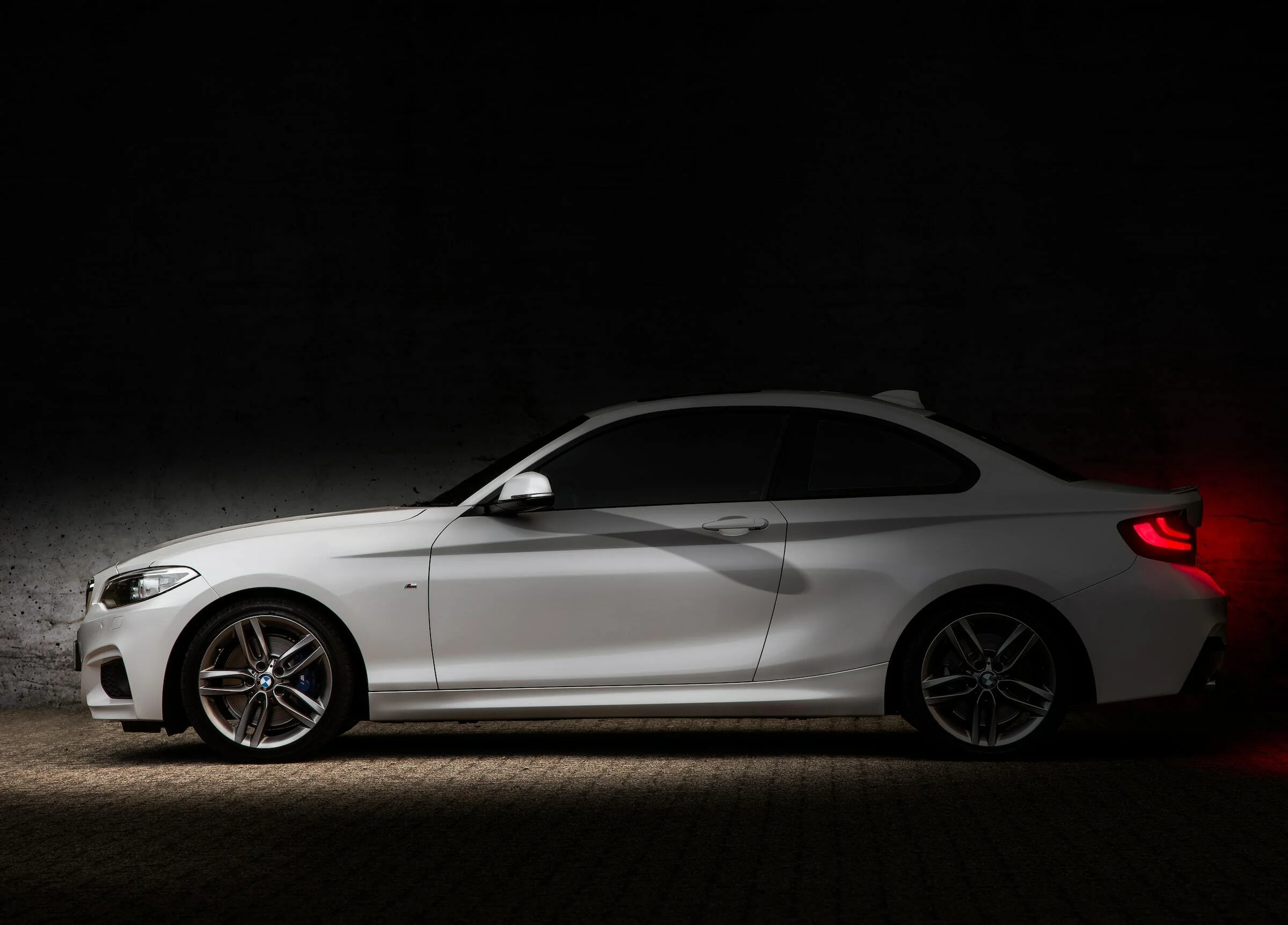 A white BMW parked up with a black background