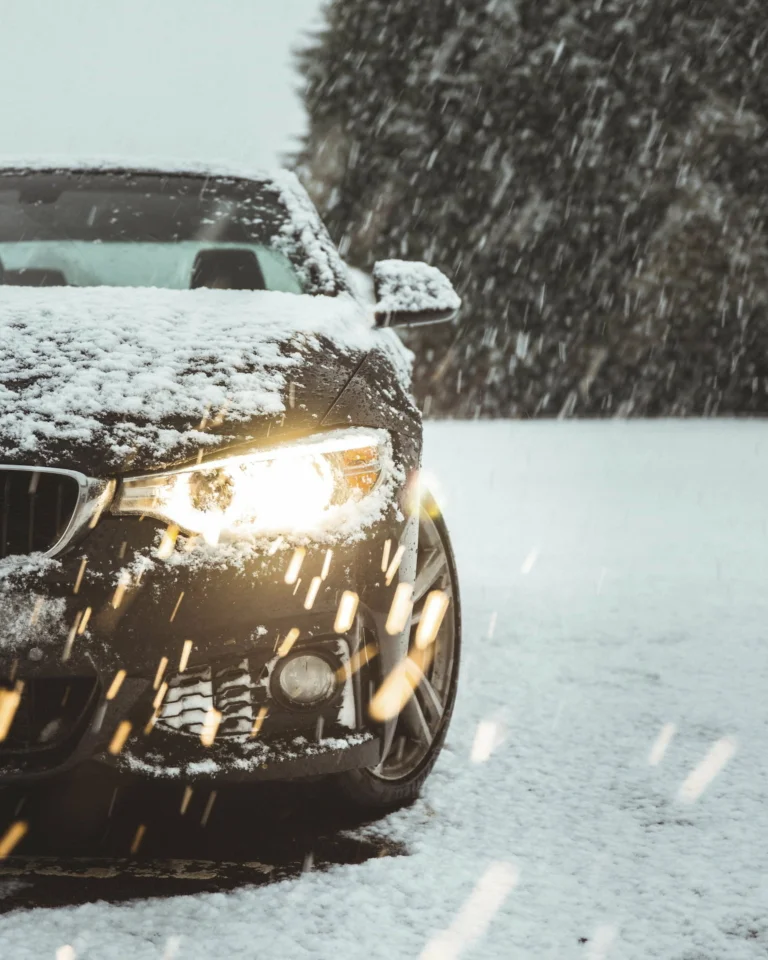 A black BMW car in the snow being damaged by the weather